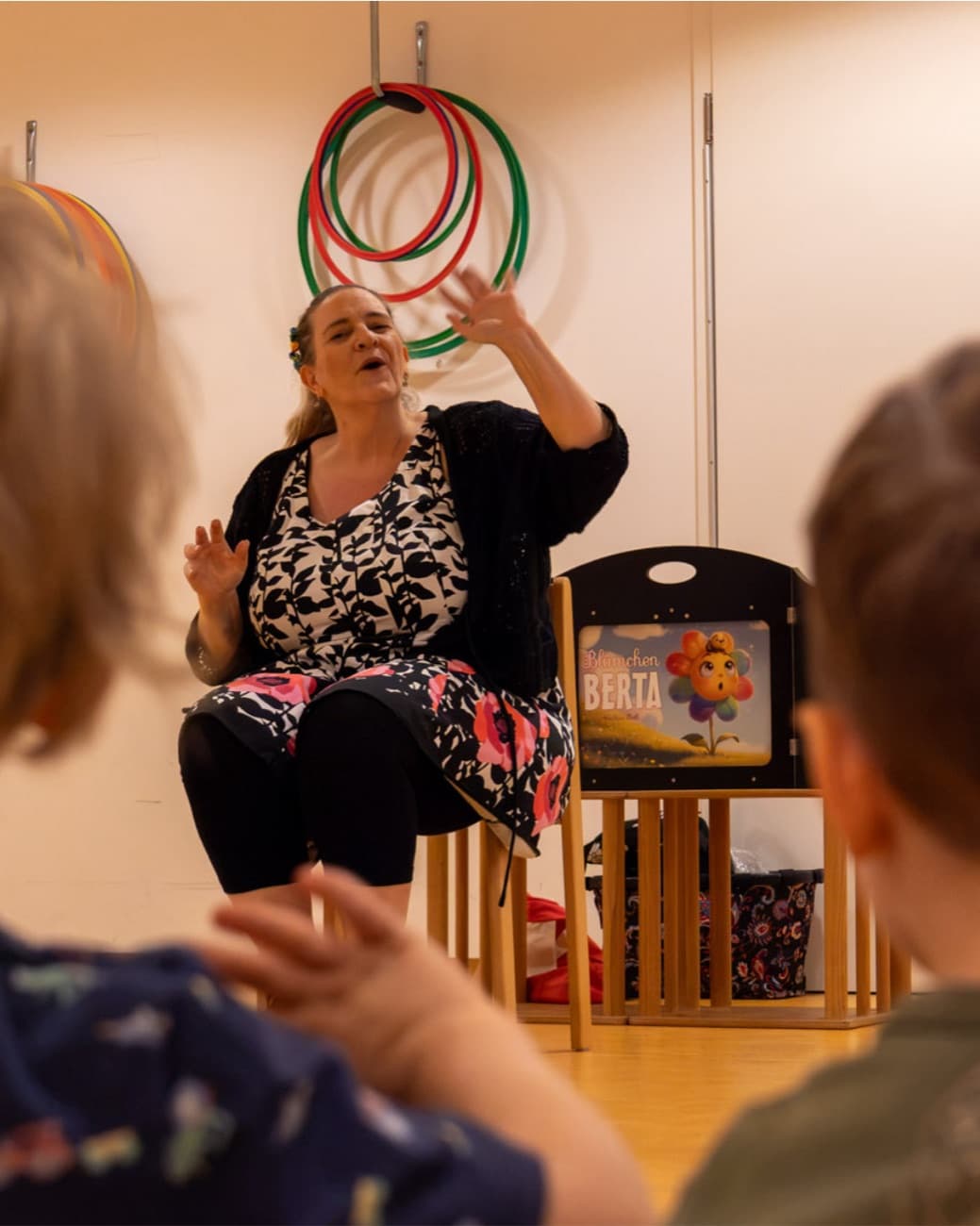 Sabine singt mit erhobenen Händen vor einer Kindergruppe